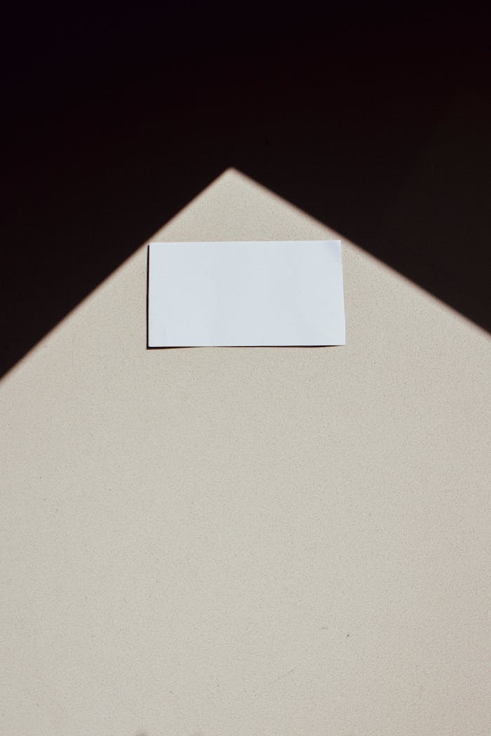 A minimalist photo of a blank business card with a geometric shadow, ideal for design concepts.